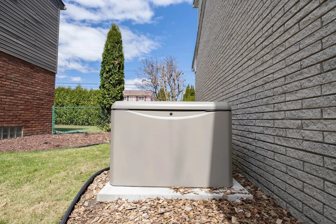 A well-kept residential Generac standby generator on a concrete pad beside a home.