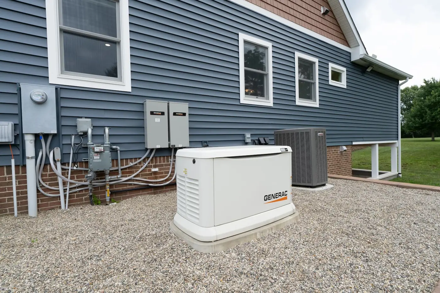 A Generac Guardian natural-gas standby generator installed on a pad beside a home.